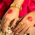 Pair of gold bangles with white enamel panels and pink flower detailing