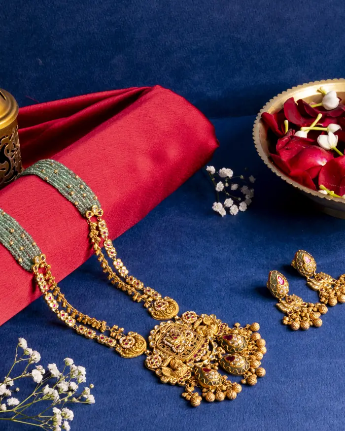 Long gold haar with emerald bead strings and matching earrings on blue silk